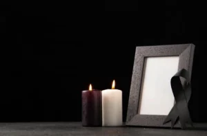 A solemn memorial display featuring a black-ribboned frame and lit candles, representing respectful funeral arrangements.