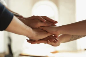 A group of people stacking their hands together in a gesture of support and solidarity, representing the commitment of the foundation in Ventura County to the community.