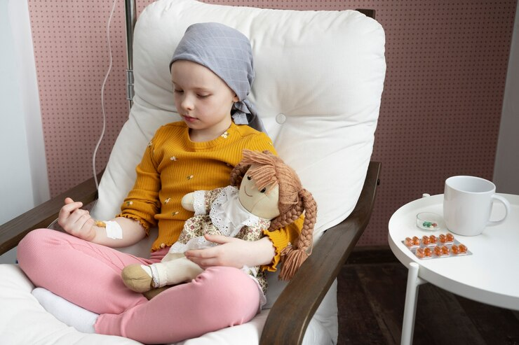 A young child undergoing cancer treatment, holding a doll while sitting on a chair, highlighting the emotional support needed during therapy.